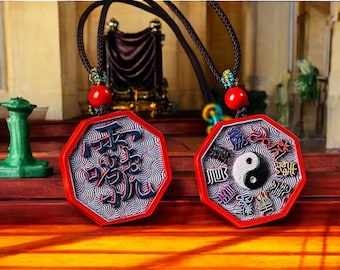 Puede incluir: Dos colgantes octogonales en cordones negros con cuentas rojas. Un colgante presenta un símbolo yin yang rodeado de caracteres chinos. El otro colgante presenta caracteres chinos en un patrón de remolino.