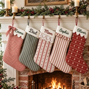 May include: Five personalized Christmas stockings hanging in a row. The stockings feature various patterns including red gingham, green stripes, and red reindeer prints, with names Emma, Dad, Mom, Sophie, and Oliver embroidered on the white cuffs.