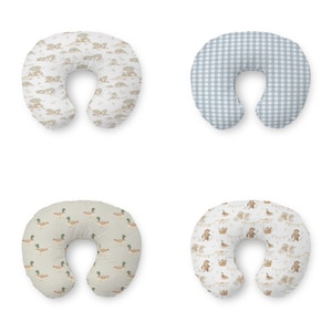 Puede incluir: Cuatro almohadas de lactancia con diferentes diseños. La almohada superior izquierda tiene un estampado beige de animales de safari. La almohada superior derecha tiene un patrón de cuadros azules y blancos. La almohada inferior izquierda tiene un patrón de patos. La almohada inferior derecha tiene un patrón de osos y bicicletas.