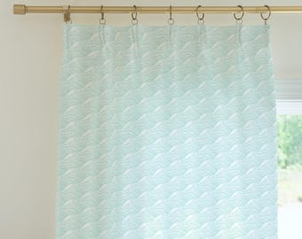 May include: A light blue curtain with a white wave pattern. The curtain is hung on a gold rod.