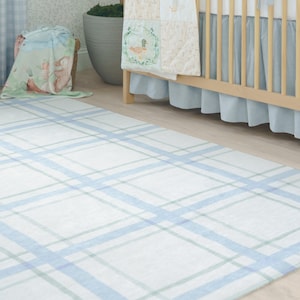 Könnte beinhalten: Rechteckiger Teppich mit weißem Hintergrund und einem Karomuster in Hellblau und Grün. Der Teppich liegt auf einem Holzboden, im Hintergrund sind ein Kinderbett und andere Artikel für das Kinderzimmer zu sehen.