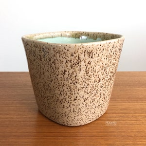 May include: A set of three ceramic mugs with a speckled, matte finish. The mugs are in shades of cream, light gray, and dark gray. Each mug has a simple, minimalist design, perfect for coffee or tea.