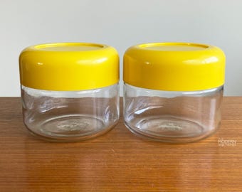 Set of 2 Modern Heller Glass Storage Jar Canisters Yellow Plastic Lids // Condition: Sm. flake on 1 jar rim ~ Scuffs,scratches to plastic