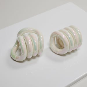 May include: A white ceramic mug with a black handle and the text "But First, Coffee" in a black, bold font. The mug is on a white surface.