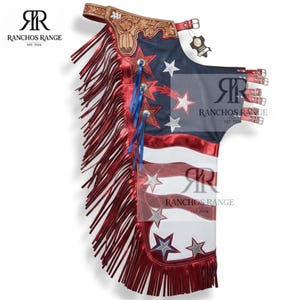 May include: Leather chaps featuring a patriotic American flag design with red, white, and blue colours. The chaps include long red fringe, silver star appliqués, a tan tooled leather waistband, and multiple adjustable buckle straps on the side.