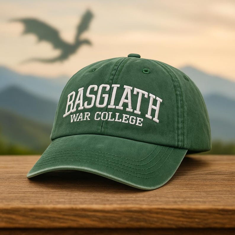 May include: A green baseball cap with the text "BASGIATH WAR COLLEGE" embroidered in white. The cap is made of a soft material and has a curved brim. A dragon silhouette is visible in the background.
