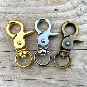 May include: Three metal keychains with swivel clips. The keychains are gold, silver, and antique brass.