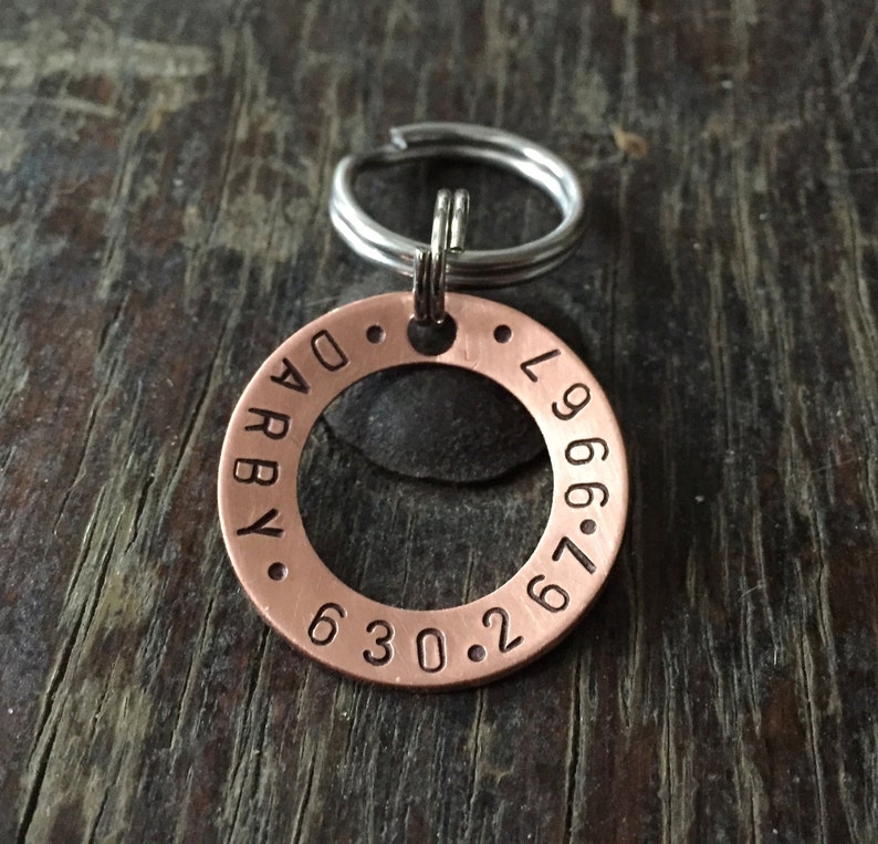 May include: Copper dog tag with the text "ARBY" and "L966.67.630.2" engraved around the edge.