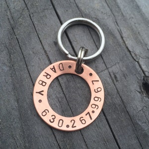 May include: Copper dog tag with a silver key ring. The tag is engraved with the text "DARBY" and the phone number "267.630.9967".