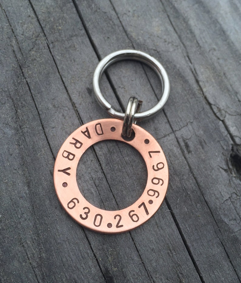 May include: Copper dog tag with a silver key ring. The tag is engraved with the text "DARBY" and the phone number "267.630.9967".