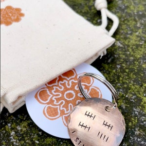 Peut inclure: Un porte-cl&eacute;s en cuivre avec les mots "I Still Do" grav&eacute;s dessus. Le porte-cl&eacute;s comporte une s&eacute;rie de lignes verticales repr&eacute;sentant des ann&eacute;es de mariage.