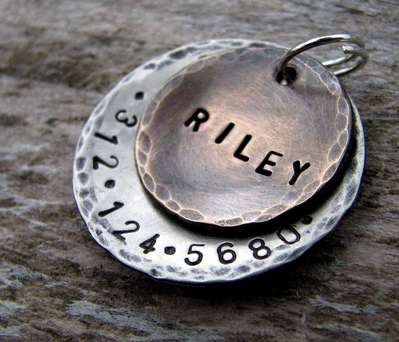 1" Aluminum disc hand stamped with a phone number is behind a 3/4" pet tag stamped with the name "Riley" . Tag hangs from a small split ring.