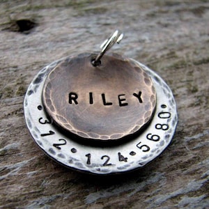1" Aluminum disc hand stamped with a phone number is behind a 3/4" pet tag stamped with the name "Riley" . Tag hangs from a small split ring.