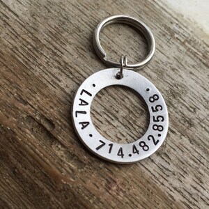 May include: Silver keyring with a round tag engraved with "LALA. 714.482.8588".