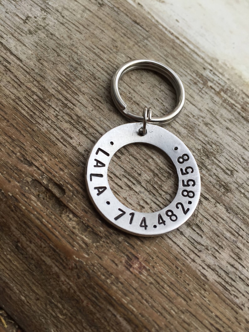 May include: Silver keyring with a round tag engraved with "LALA. 714.482.8588".