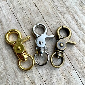 Op de afbeelding: Drie metalen draaibare sluitingen in goud, zilver en antiek messing. Elke sluiting heeft een ronde ring en een haak.