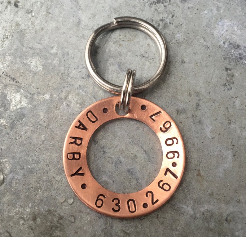 May include: A copper dog tag engraved with the name "Darby" and the phone number "630.267.9669". The tag is attached to a silver key ring.