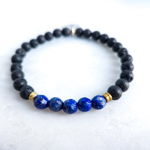 May include: A beaded bracelet featuring black lava rock beads and vibrant blue lapis lazuli stones. The bracelet includes gold-colored spacers and is strung on an elastic cord. This piece is suitable for everyday wear.