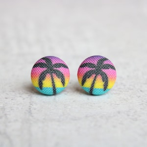 May include: A pair of colorful fabric earrings with a palm tree silhouette on a sunset background.