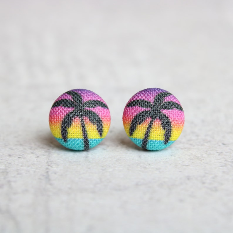 May include: A pair of colorful fabric earrings with a palm tree silhouette on a sunset background.