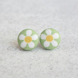 May include: A pair of green fabric earrings with white daisy flower designs and yellow centers.