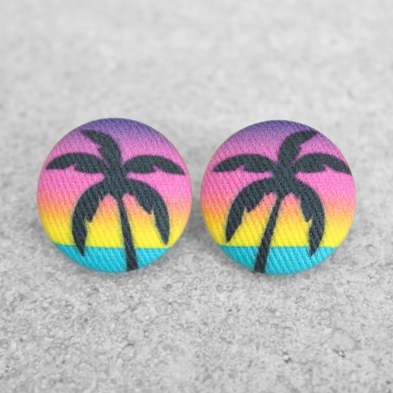 May include: A pair of colorful fabric earrings with a palm tree silhouette on a sunset background.