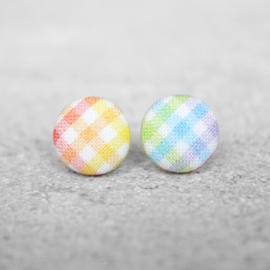 May include: A pair of rainbow gingham fabric button earrings. The earrings are round and have a white background with rainbow colored gingham squares.