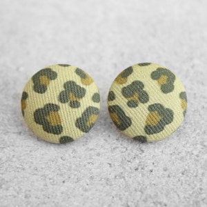 May include: A pair of round, yellow and green fabric earrings with a leopard print pattern.