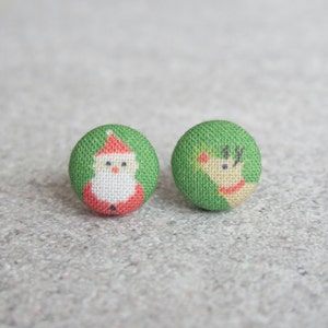 May include: A pair of green fabric Christmas earrings. One earring features a Santa Claus design and the other features a reindeer design.