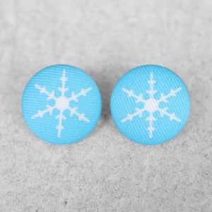 May include: A pair of blue fabric button earrings with white snowflake designs.