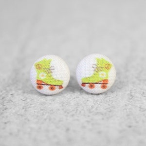 May include: A pair of white button earrings with a green roller skate design.