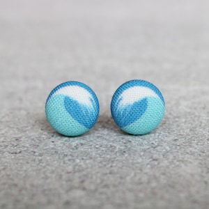 May include: A pair of blue and white fabric stud earrings with a wave pattern.