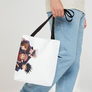 May include: White tote bag with a black handle featuring a colorful illustration of four anime characters. The characters are in dark blue and black outfits with various hair colors, including brown, pink, and white.