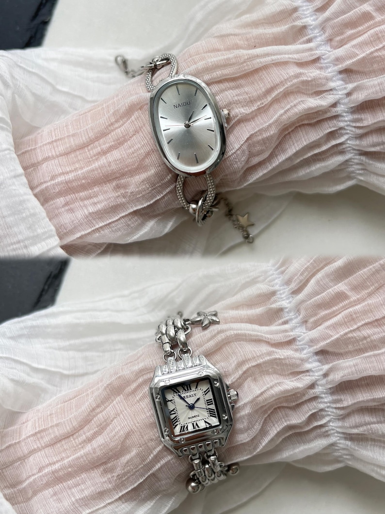 K&ouml;nnte beinhalten: Zwei silberne Uhren mit Gliederarmb&auml;ndern. Die obere Uhr hat ein ovales Zifferblatt mit dem Wort "NAIDU" darauf. Die untere Uhr hat ein quadratisches Zifferblatt mit r&ouml;mischen Ziffern und dem Wort "QUARTZ" darauf.