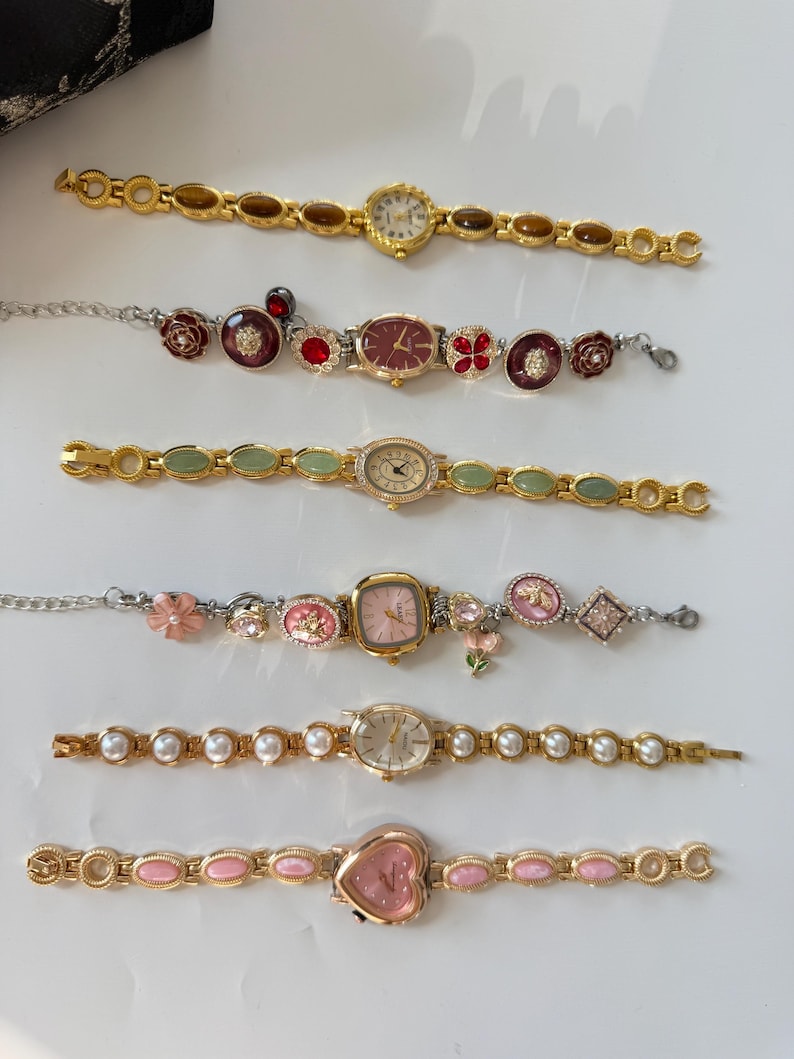May include: Collection of gold-toned and silver-toned wristwatches with various designs. Features include watches with floral, pearl, and gemstone accents. The watch faces are round, oval, and heart-shaped, with analog displays.