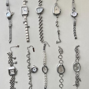 K&ouml;nnte beinhalten: Zehn silberne Armbanduhren mit verschiedenen Band- und Zifferblattstilen. Einige der B&auml;nder haben Charms.