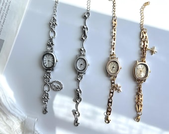 May include: Four vintage-style wristwatches with oval faces and delicate chain straps. Two are silver-toned, and two are gold-toned. One silver watch has a religious charm. The gold watches have star and charm accents.