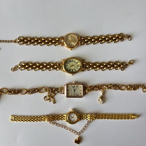 Puede incluir: Cuatro relojes de pulsera de tono dorado con diferentes estilos de esferas y correas. Las correas est&aacute;n hechas de cadenas de metal enlazadas.