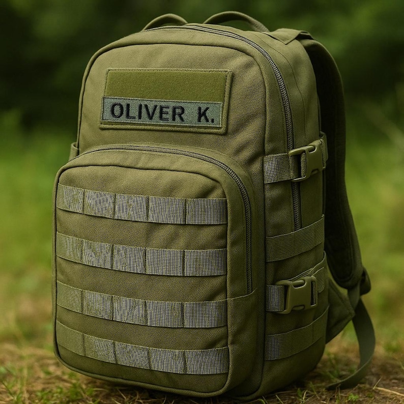 Pode incluir: Mochila t&aacute;tica verde-oliva com v&aacute;rios compartimentos, correias e fivelas. A mochila apresenta o nome "OLIVER K." em um patch. A bolsa &eacute; projetada para atividades ao ar livre e viagens.