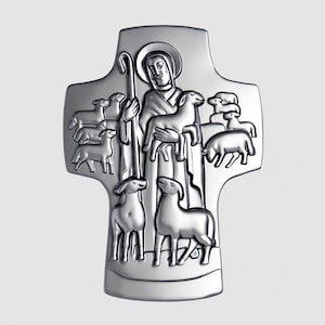 以下が含まれることがあります： 銀色の十字架型の宗教ペンダント。羊を抱える羊飼いが描かれ、羊に囲まれています。羊飼いは光輪と杖を持っています。デザインは詳細なレリーフでエンボス加工されています。