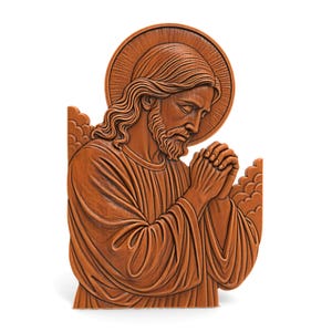 Puede incluir: Escultura en relieve de madera que representa una figura con pelo largo, barba y halo, con las manos juntas en oración. La escultura está tallada en un tono marrón cálido, con rasgos faciales detallados y túnicas fluidas. La figura está sobre un fondo blanco.