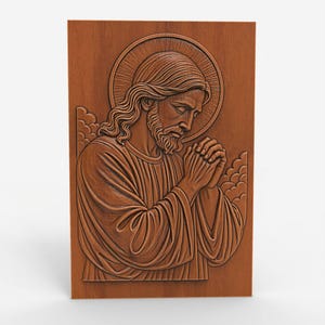 Puede incluir: Un relieve de madera que representa una figura religiosa con un halo, las manos juntas en oración y túnicas fluidas. El relieve es en tonos marrones y presenta texturas y líneas detalladas.