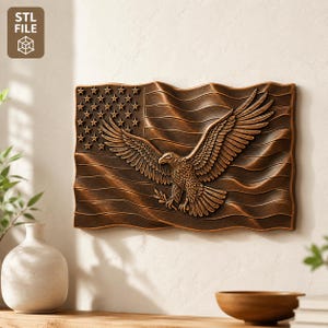 May include: A bronze-colored wall art piece depicting the American flag with a detailed eagle in flight. The flag's stars and stripes are visible, and the eagle holds an olive branch. The piece is mounted on a neutral-colored wall.