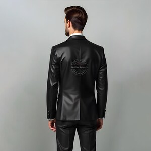 May include: A black leather blazer and matching pants. The blazer has a classic two-button design and notched lapels. The back of the blazer has a circular logo that reads "Leather Synergy" and "Keep it Simple, Live in the Moment."