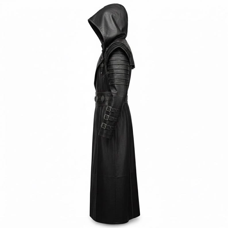 Puede incluir: Un abrigo largo de cuero negro con dise&ntilde;o de capucha. El abrigo presenta una cintura con cintur&oacute;n, detalles en los hombros y m&uacute;ltiples hebillas. El abrigo est&aacute; dise&ntilde;ado con una falda larga y fluida.