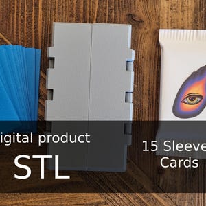 Puede incluir: Varios objetos sobre una superficie de madera. Incluye una pila de cartas azules con texto manuscrito, un contenedor gris plegable y un paquete blanco con un diseño gráfico y el texto "15 Sleeved Cards". También está presente el texto "Digital product STL".
