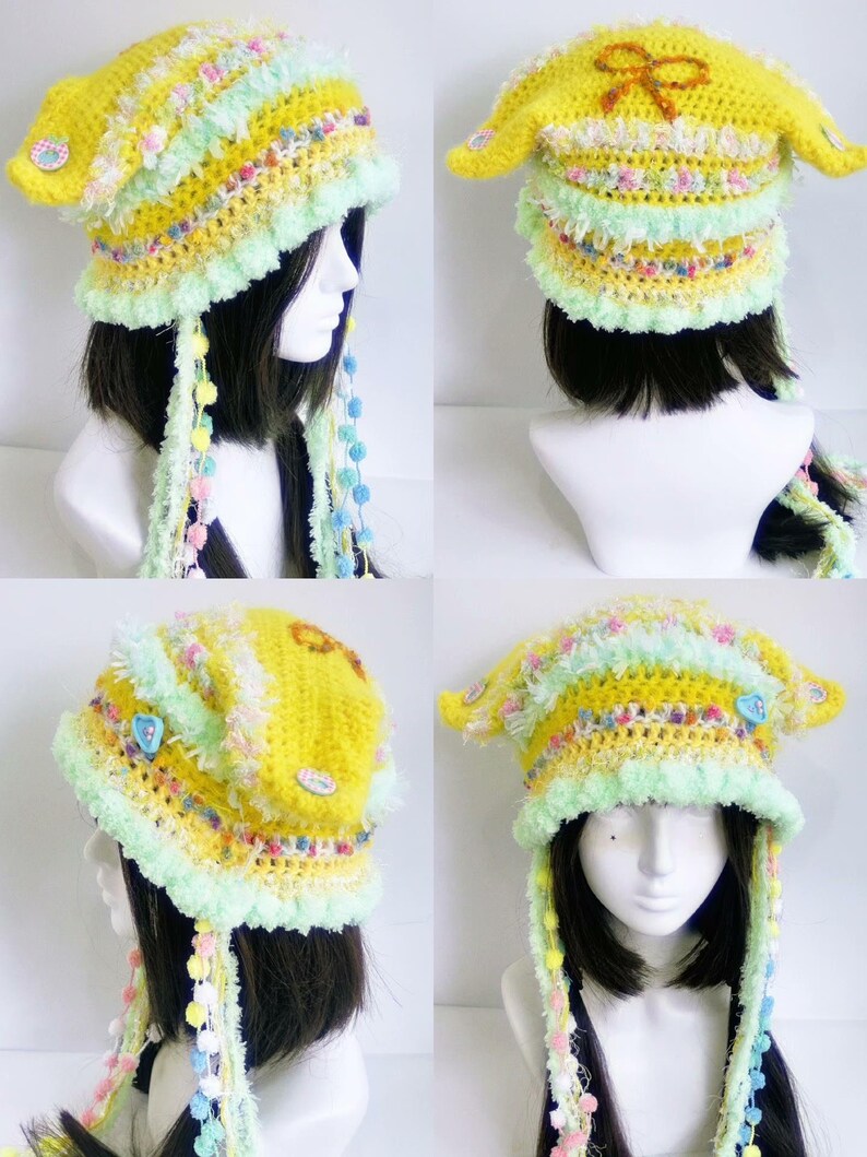 May include: A handmade yellow crochet hat with a whimsical design. The hat features a ruffled brim, pastel accents, and dangling beaded strands. The hat is adorned with decorative buttons and a bow.