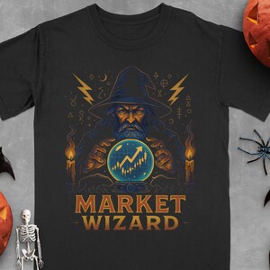 May include: Black t-shirt featuring a wizard with a long beard and a pointed hat, gazing into a crystal ball with a stock market graph. The text "MARKET WIZARD" is below the image. Halloween-themed design.