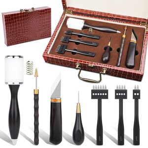 Pode incluir: Um conjunto de ferramentas para artesanato em couro com uma caixa de couro sint&eacute;tico castanha. O conjunto inclui v&aacute;rias ferramentas como um ma&ccedil;o, pun&ccedil;&otilde;es, uma faca e um sulcador de costura. As ferramentas t&ecirc;m cabos de madeira escura e detalhes prateados ou dourados. A caixa est&aacute; fechada.