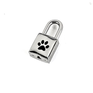 May include: Silver padlock with a black paw print design.